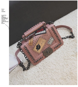 Detailed close-up of pink crossbody bag featuring vintage patches and metal studs