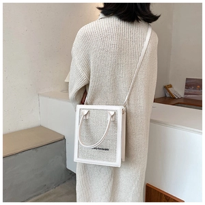 Chic cream-white woven crossbody bag shown on model with branding detail and slim strap