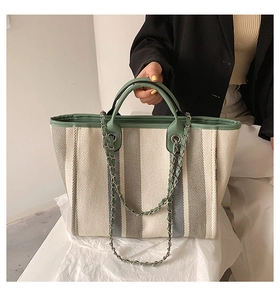 Détail du sac cabas en toile à rayures vert menthe avec chaîne et anse en cuir