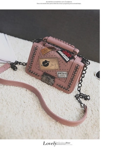 Pink pebbled leather crossbody bag with metal chain, rivets and stylish patchwork badges
