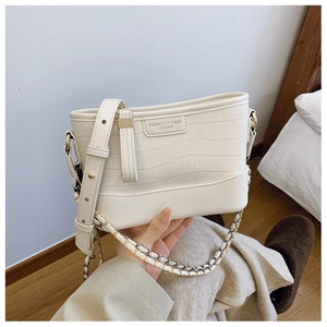 Close-up of off-white crocodile pattern shoulder bag with golden chain and leather strap