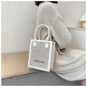 Close-up of a stylish white leather and tweed small square bag held by a model