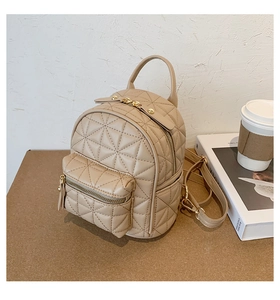 Close-up of beige quilted mini backpack with gold zippers and star patterns