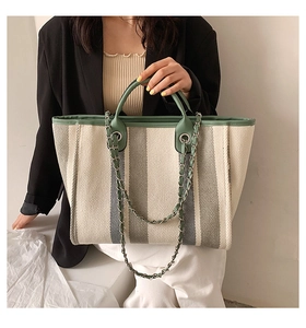 Détail d'un sac cabas à rayures avec bordure en cuir vert et poignée en chaîne métallique