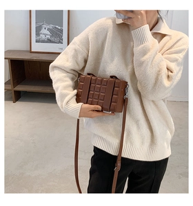 Detail view of brown quilted box bag with chocolate embossed pattern and shoulder strap