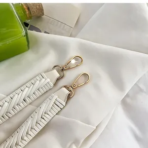 Détail d'une bandoulière tressée en cuir crème avec des fermoirs en métal doré