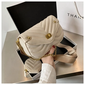 Détail du sac bandoulière crème matelassé avec finitions dorées et pochette ronde