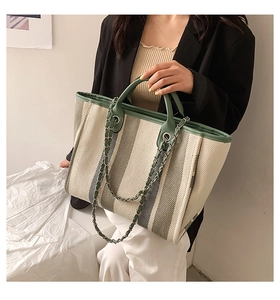 Détail du cabas en toile avec garniture en cuir vert et bandoulière chic en chaîne métal