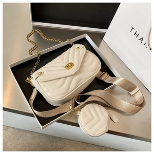 Détail d'un sac bandoulière beige matelassé avec chaîne dorée et large bandoulière amovible