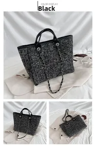 Detail of black and white tweed woven tote bag with leather handles and chain strap