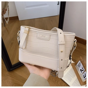 Detailed close-up of cream crocodile pattern leather bucket bag with gold hardware