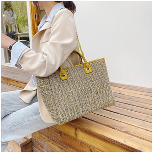 Detail view of woven plaid fabric and yellow leather trim on large bucket tote bag