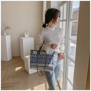 Close-up of blue and white ethnic woven bucket bag with elegant metal chain detail