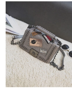 Detailed close-up of grey PU leather crossbody bag with metal rivets and fashion patches