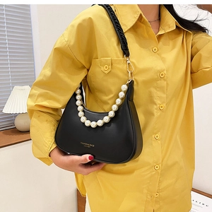 Détail du sac demi-lune noir avec chaîne en perles blanches et bandoulière tissée