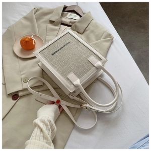 Macro shot of minimalist beige leather crossbody bag with woven texture and top handles