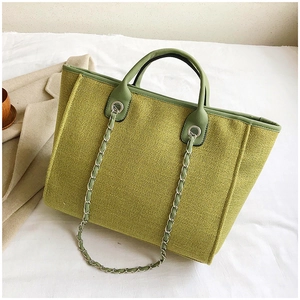 Detail of avocado green tote bag featuring woven texture and silver metal eyelet chain