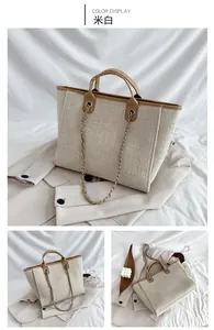 Detail view of off-white woven tote bag with brown leather trim and metal chain strap