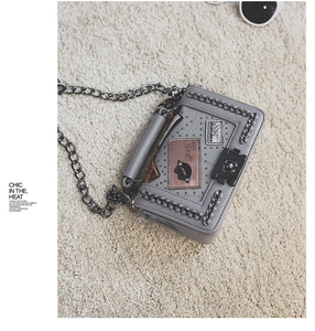 Close-up of gray punk style flap bag with metal studs, creative patches and chain strap
