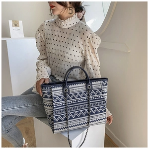 Detail of blue and white ethnic woven tote bag featuring silver chain strap and leather handles