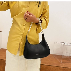 Détail d'un sac à main noir avec poignée en perles et bandoulière en chaîne dorée