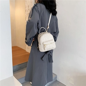 Chic white quilted faux leather mini backpack with gold hardware worn over a grey coat