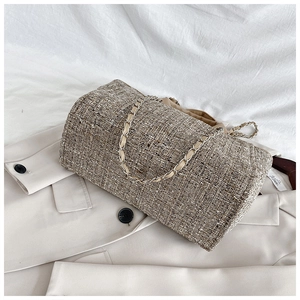 Close-up of textured brown tweed bucket bag with woven metal chain strap detail
