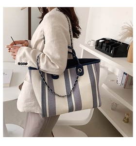 Détail du sac cabas en toile montrant le motif rayé et la bandoulière en chaîne de cuir