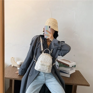 White quilted faux leather mini backpack with geometric diamond pattern and adjustable straps