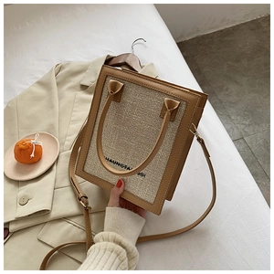 Detail of a khaki PU leather and beige canvas square tote bag with elegant black lettering