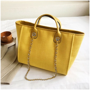 Detail of lemon yellow tote bag with chain strap on a cozy minimalist lifestyle background