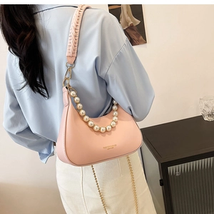 Sac bandoulière demi-lune rose avec anse en perles et sangle tissée sur modèle