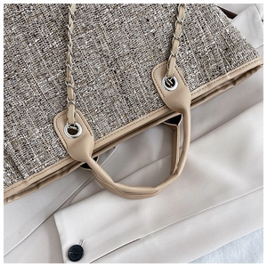 Close-up of brown tweed fabric and beige leather trim on a spacious tote bag