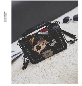 Close-up of black PU leather crossbody bag with decorative patches and metal lock
