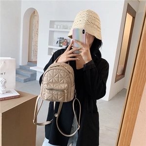 Beige quilted leather mini backpack with adjustable straps shown in mirror selfie