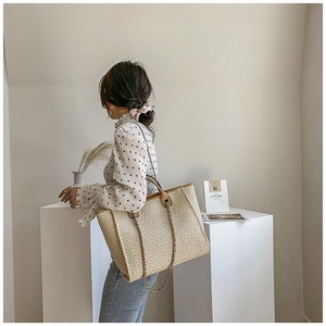 Detail of light brown tote bag featuring geometric rhombus patterns and metal chain strap