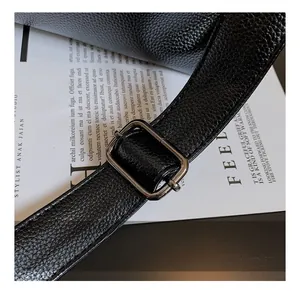 Detail shot of black lychee grain leather shoulder strap with dark metal buckle