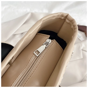 Macro detail of the beige faux leather tote showing silver zipper and black fabric lining