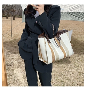 Détail du sac cabas en toile rayée avec bordure en cuir marron et bandoulière chaîne