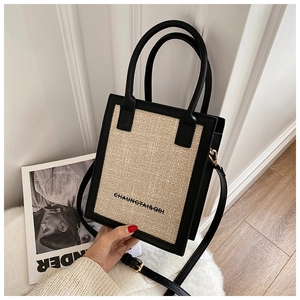 Close-up of beige woven mini square bag with black leather trim and gold hardware
