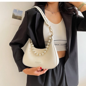 Détail d'un sac hobo crème avec poignée en perles et bandoulière tressée sur un mannequin