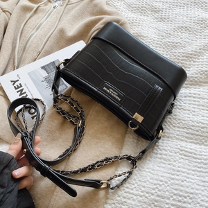 Fashionable black crocodile embossed leather bucket bag with gold chain strap on casual wear