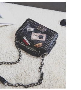 Detailed macro of black pebbled PU leather bag with rivets, patches and chain strap