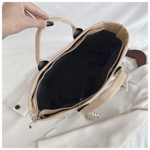 Spacious interior of beige tote bag showing black lining and zip compartment