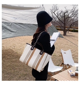 Détail du grand cabas en toile rayée avec garniture en cuir dans un cadre de camping chic