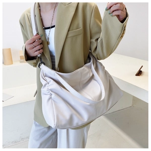 Detail showing soft lychee-patterned cream tote bag with side pleats and black metal buckle