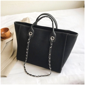 Close-up of black canvas tote bag featuring silver chain straps and leather handles