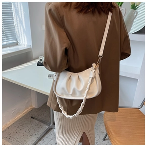 Détail du sac bandoulière blanc plissé avec poignée tressée et accents dorés