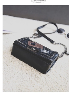 Detail of black crossbody bag featuring punk studs, chain accents and vintage patches