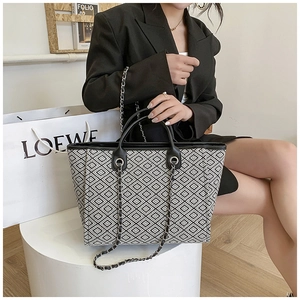 Detail of checkered woven tote bag featuring black leather handles and metal chain strap